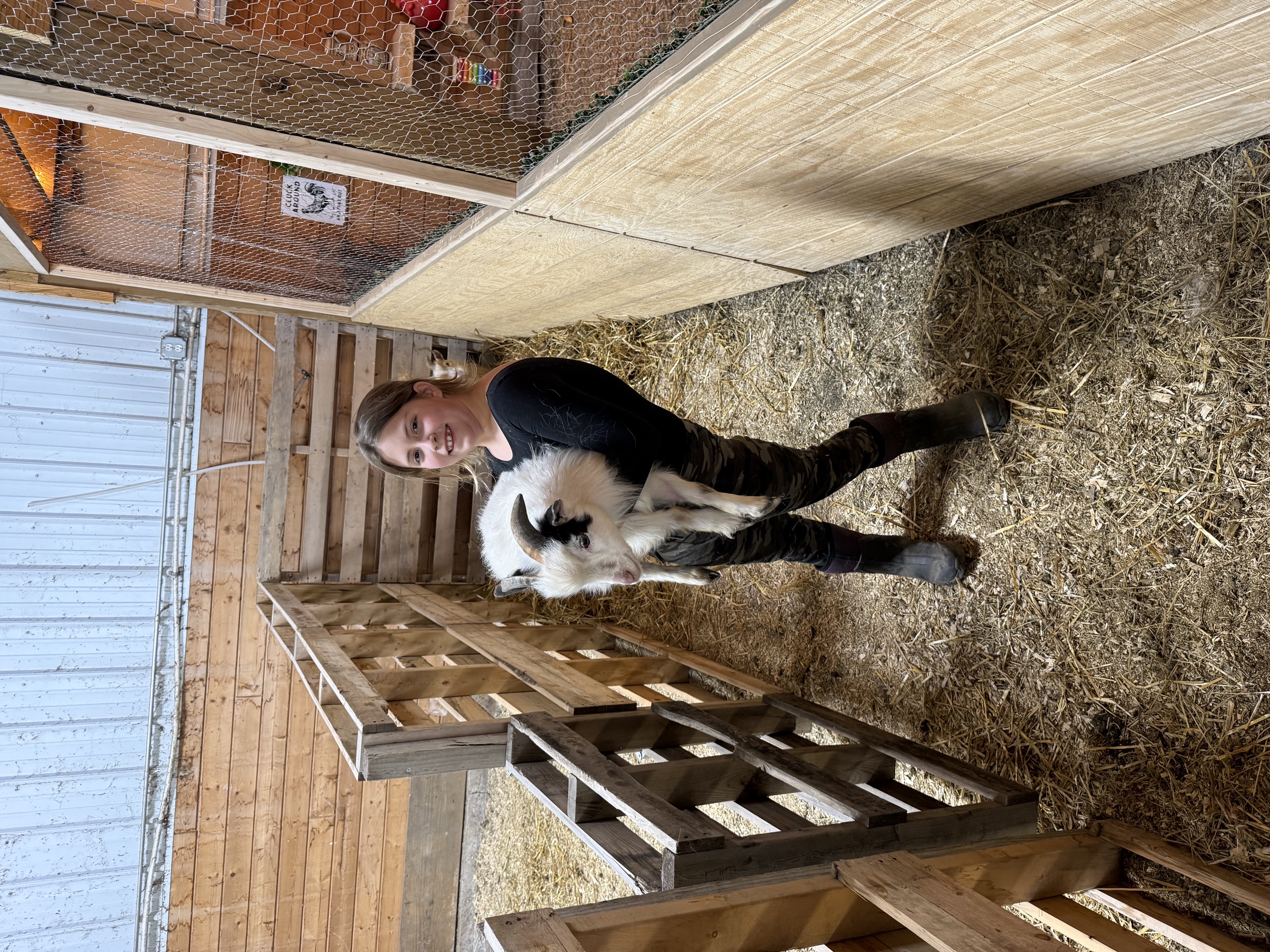 Kid holding Mario the goat in the barn